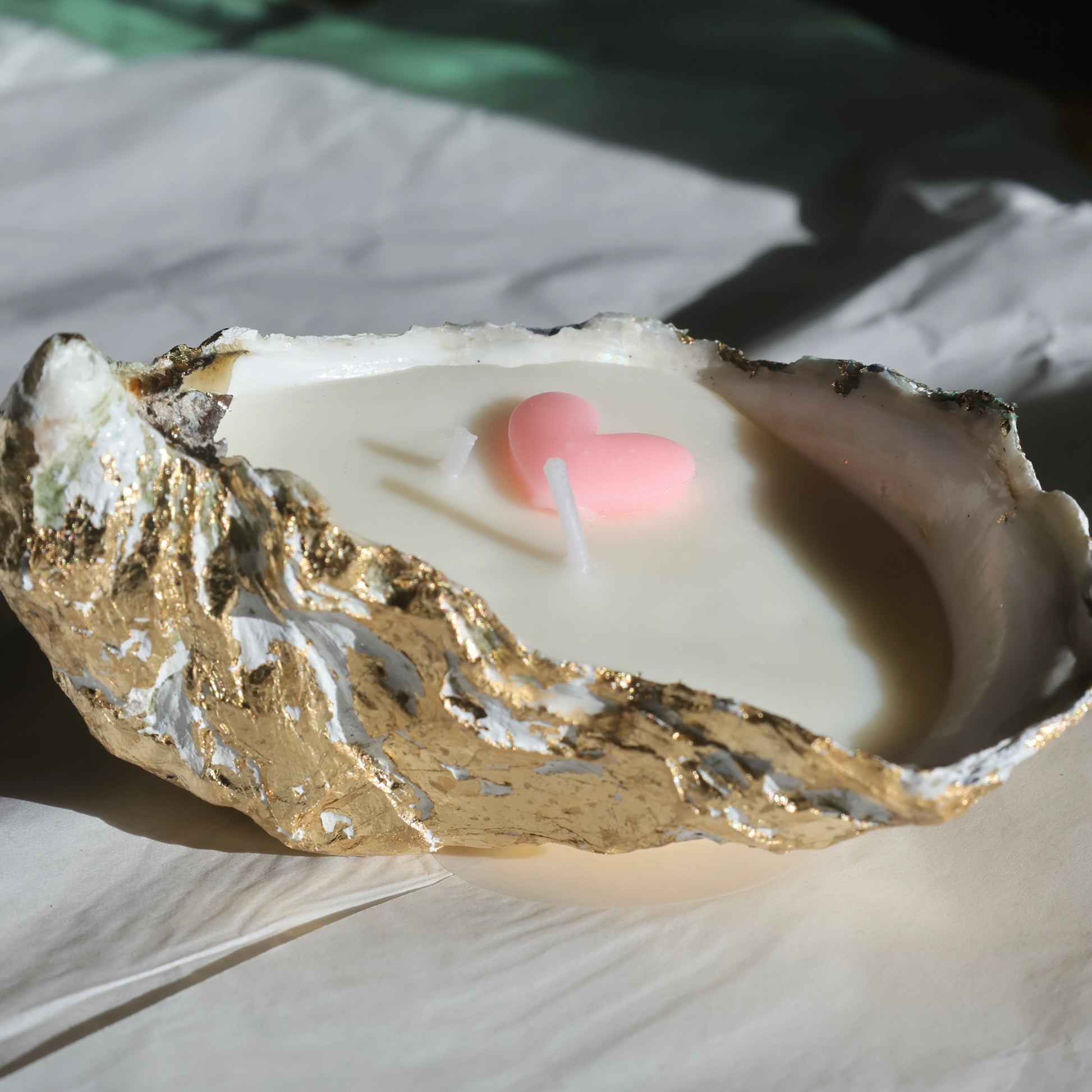 Oyster shell candle with a pink heart detail on crumpled white background by Lily Glow Home Decor