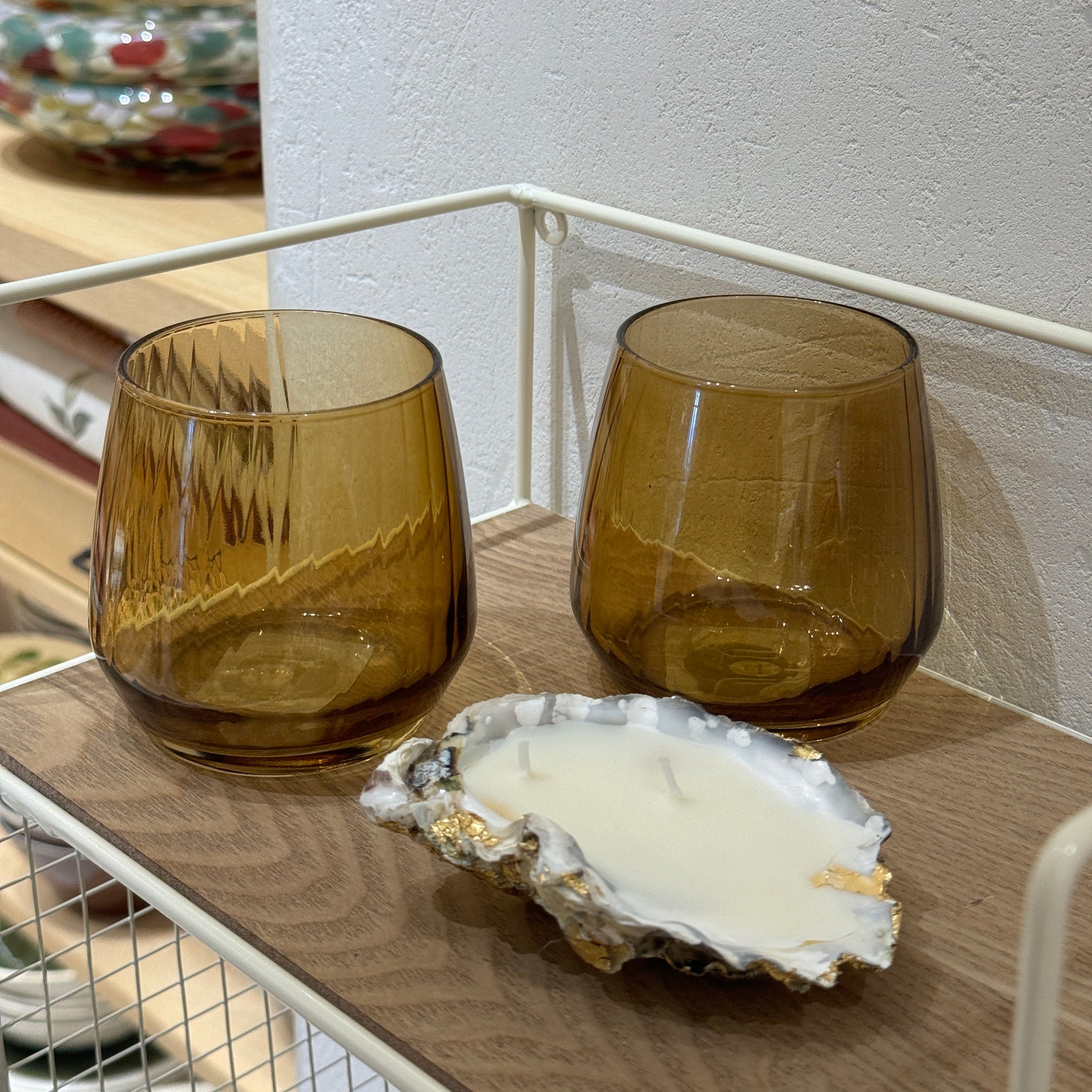 Oyster shell candle by Lily Glow Home Decor  with white wax and gold accents next to amber glasses