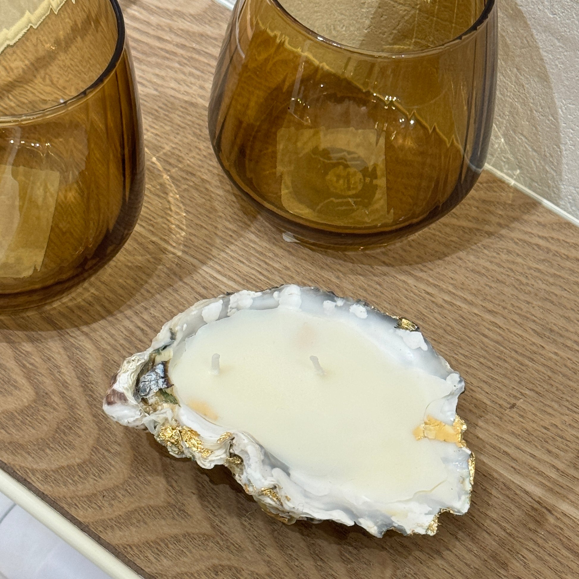 White wax candle in a natural oyster shell by Lily Glow Home Decor  on a wooden surface
