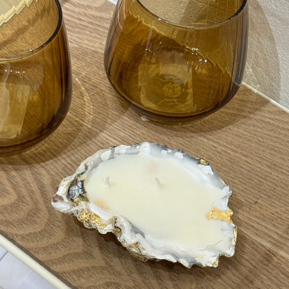 White wax candle in a natural oyster shell by Lily Glow Home Decor  on a wooden surface